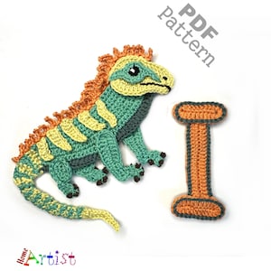 May include: Crochet pattern for a green and orange iguana with a yellow and orange tail. The pattern also includes a crochet letter I in orange and grey.