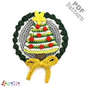 May include: A crocheted Christmas tree ornament with a green, white, and yellow tree, red pom-poms, and a yellow bow. The ornament is surrounded by a green and gray crocheted circle.