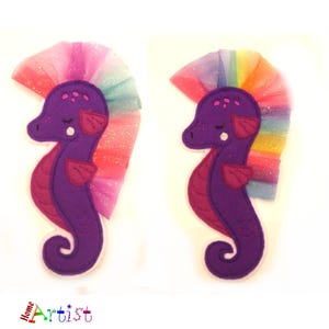 May include: Two purple felt seahorse appliques with rainbow tulle hair. Each seahorse has a white pearl and pink fins.