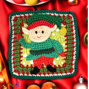 May include: A handmade crochet Christmas elf square. The elf has a cream-colored face, green outfit, red hat and pants, and black shoes. The square is green, red, and cream-colored, with a green border. Christmas decor.