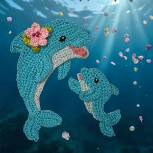 Könnte beinhalten: Zwei gehäkelte Delfine in Blau-, Grau- und Rosatönen vor blauem Hintergrund mit fallenden Blütenblättern. Ein Delfin trägt einen rosa Blumenkranz. Die Delfine scheinen zu interagieren und schaffen eine bezaubernde Unterwasserszene.