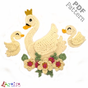 May include: Crocheted swan family with a mother swan wearing a gold crown, two baby swans, and a floral arrangement. The swans are cream-colored with yellow beaks and black eyes. The flowers have cream petals and pink centers. The text "PDF Pattern" is in the upper right corner.