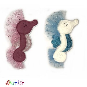 May include: Two felt seahorse ornaments with glitter accents. One is pink with a pink tulle skirt and the other is white with a blue tulle skirt.