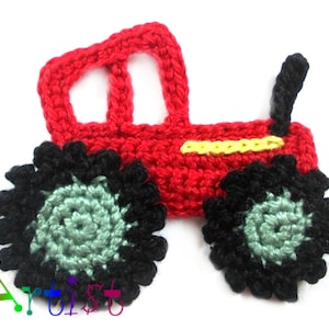 Op de afbeelding: Een rode gehaakte tractor met zwarte wielen en een gele streep. De wielen hebben een groene kern.