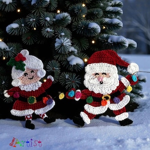 May include: Crocheted Christmas decorations of Santa Claus and Mrs. Claus, both wearing red suits with white trim and holding colourful string lights. The figures are set against a snowy backdrop with a Christmas tree.