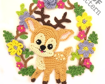 Puede incluir: Patrón de crochet para un lindo ciervo con cuernos, rodeado de una corona de flores en tonos rosa, amarillo y morado. El patrón está disponible para descargar en PDF.