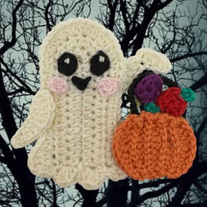 May include: A cream-colored crocheted ghost applique featuring large black eyes with white highlights, a small black mouth, and pink circular cheeks. The ghost holds a small orange crocheted pumpkin basket filled with purple, red, and teal flowers.