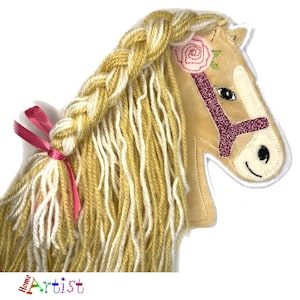 May include: A plush horse toy with a braided mane and tail made of yarn. The horse has a pink bridle and a pink flower on its head.