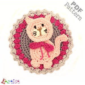Puede incluir: Patrón de crochet para un gato rosa con un lazo, rodeado de un borde de crochet gris y rosa. El patrón está disponible para descargar en PDF.