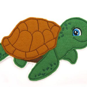 Könnte beinhalten: Eine grüne Filzturtel mit brauner Schale und blauen Augen. Die Schildkröte hat einen lächelnden Ausdruck und schwimmt.