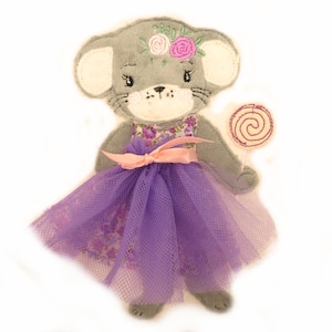 May include: A gray felt mouse wearing a purple tulle skirt with a floral print and a pink ribbon. The mouse has a pink flower crown and is holding a pink and white swirl lollipop.