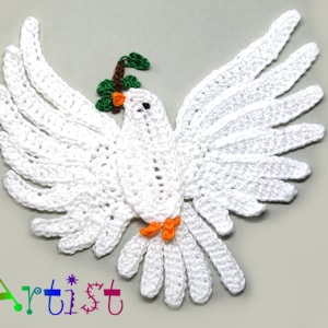 Könnte beinhalten: Weiße gehäkelte Taube mit ausgebreiteten Flügeln, die einen grünen Olivenzweig im Schnabel hält. Die Taube ist ein Symbol des Friedens.