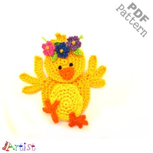 May include: A crocheted yellow chick with orange feet and a flower crown. The crown has pink, purple, blue, and green flowers.