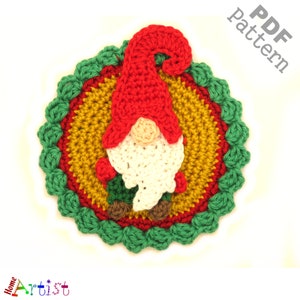 May include: Crocheted gnome ornament with a red hat, white beard, and green and brown accents. The gnome is sitting on a green and yellow crocheted circle.