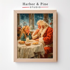 May include: Framed print of Santa Claus and a young girl at a table. Santa, in a red suit, sits across from the girl, who wears a blue dress. A table with cookies, milk, and pastries is between them. The print is in a light wood frame. The text "Harbor & Pine Studio" is at the top.