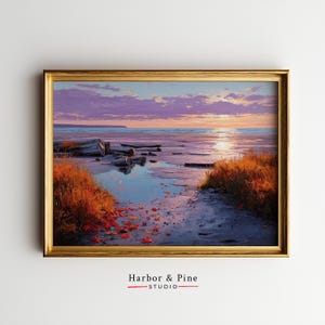 May include: A framed landscape painting depicts a serene beach scene at sunset. The artwork features a golden frame, a sandy shore, and vibrant colors of orange, purple, and blue. The text "Harbor & Pine STUDIO" is at the bottom.