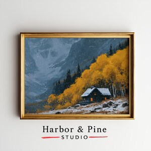 May include: A framed landscape painting depicting a dark cabin with glowing windows nestled among vibrant yellow autumn trees and snow-covered ground, set against a backdrop of towering, snow-dusted mountains under a light snowfall.