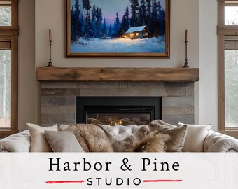 May include: A framed landscape painting of a snow-covered forest with a cabin, above a fireplace. The painting has a gold frame and is mounted above a wooden mantel. The text "Harbor & Pine STUDIO" is at the bottom.