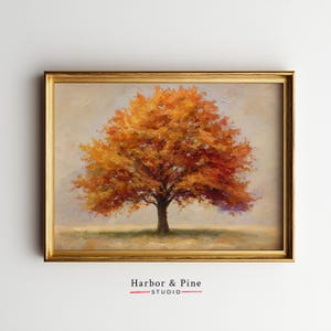 May include: A framed oil painting depicting a tree with autumnal orange and red leaves, set against a soft, neutral backdrop. The tree's dark trunk and branches contrast with the colourful foliage. The frame is gold, and the text "Harbor & Pine Studio" is at the bottom.