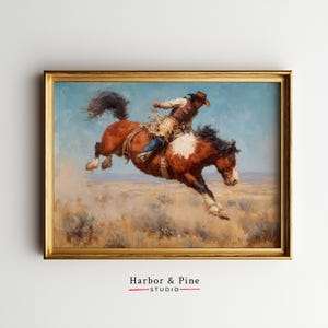 May include: A framed vintage painting depicts a cowboy riding a bucking bronco. The horse is brown and white, with a dark mane and tail. The cowboy wears a hat, vest, and chaps. The background shows a blue sky and a grassy plain. The frame is gold.