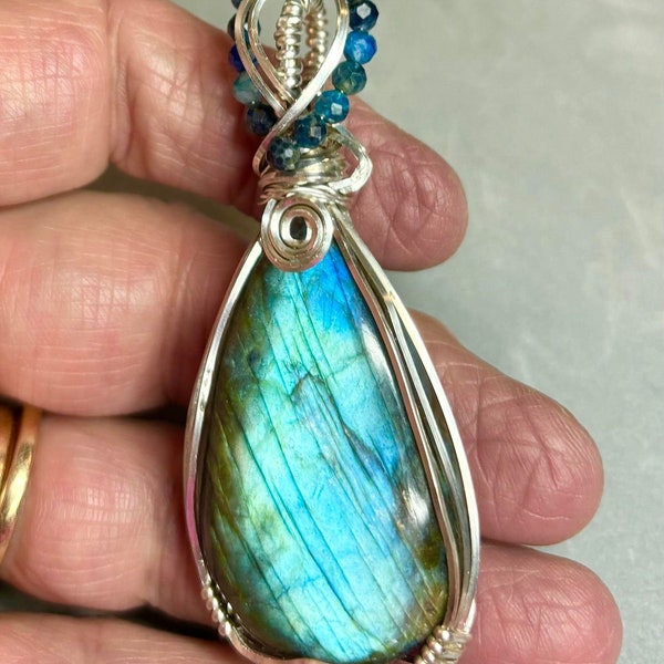 Gorgeous blue flash labradorite wire wrapped in sterling silver wire. 1.1 inch x  x 2.7 inch. Adorned with kyanite beads.