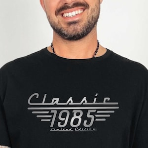 May include: A black t-shirt with a silver graphic that says "Classic 1985 Limited Edition".