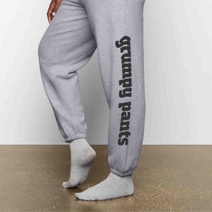 May include: Gray sweatpants with the text "Grumpy Pants" printed vertically on the right leg.