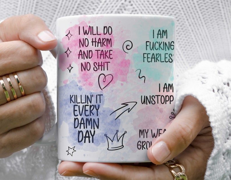 May include: White ceramic mug with a watercolor background and black text that reads "I will do no harm and take no shit", "I am fucking fearles", "I am killin' it every damn day", "I am unstopp", "My we grow", and other motivational phrases.
