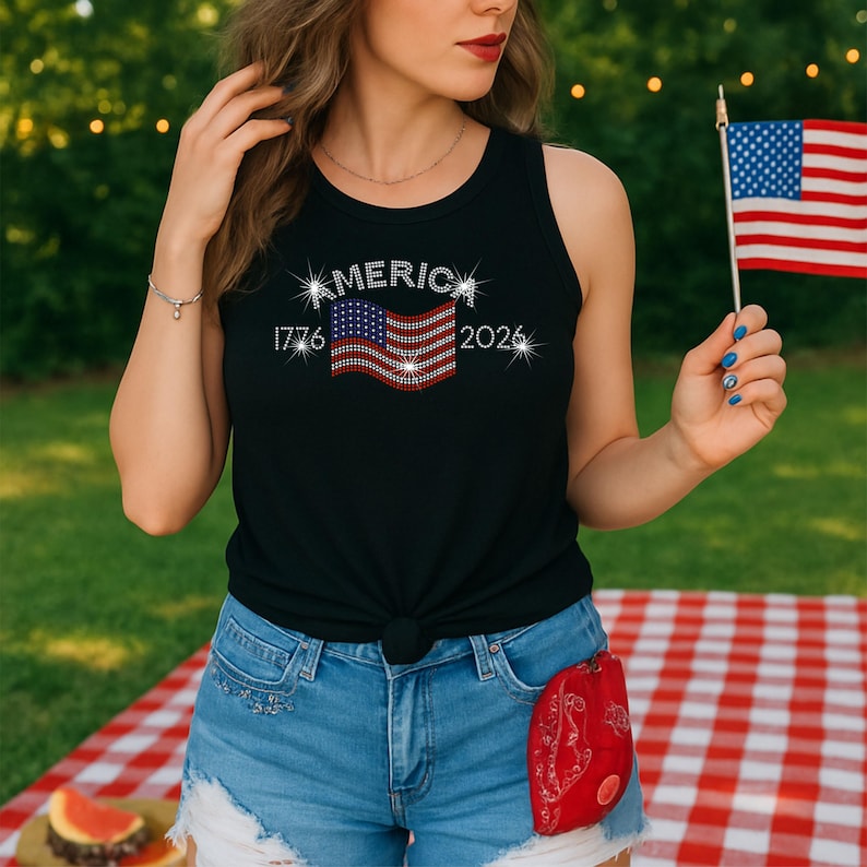 Woman at picnic holding small USA flag, wearing black Tank with a rhinestone America 1776 - 2006 design.