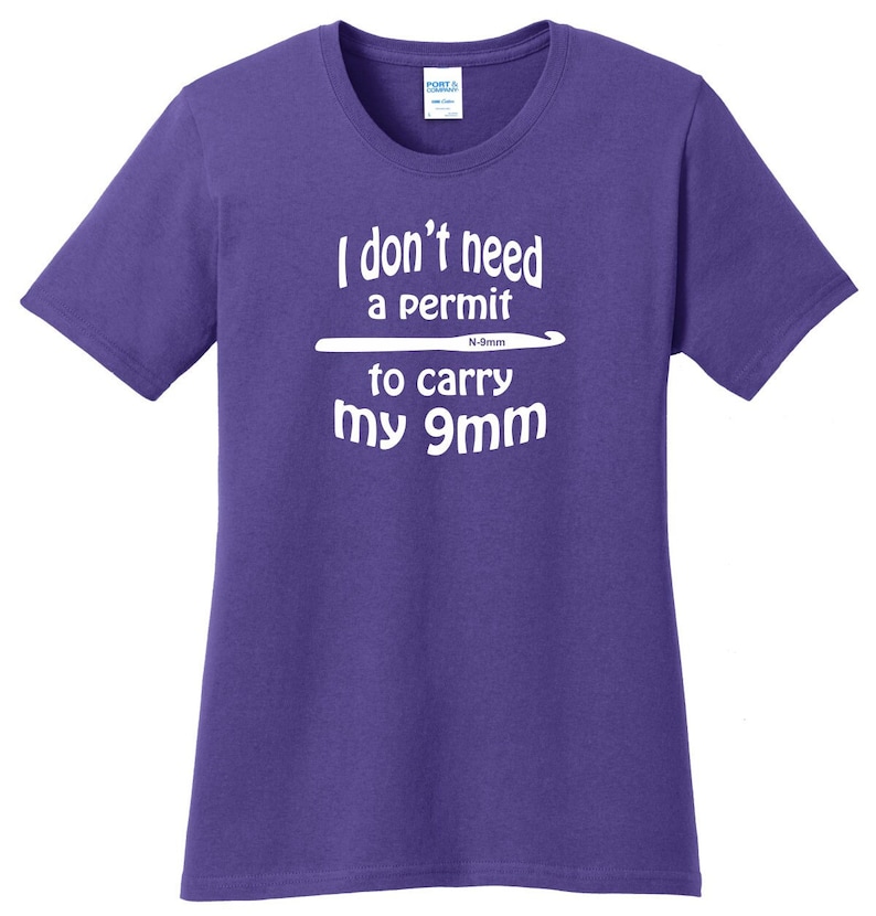 Peut inclure: T-shirt violet avec un texte blanc qui dit "Je n'ai pas besoin de permis pour porter mon 9mm" avec un crochet blanc au-dessus du texte.