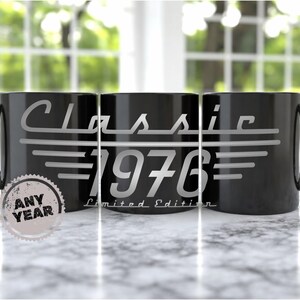 May include: Three black ceramic mugs with the words "Classic 1976" in a silver font. The mugs have a handle on the right side. The words "Limited Edition" are below the year. A circular sticker on the left mug says "Any Year".