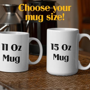 May include: Two white ceramic mugs with black text. The mug on the left says "11 Oz Mug" and the mug on the right says "15 Oz Mug".