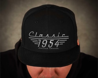 Może przedstawiać: Czarna czapka z daszkiem z haftowanym srebrnym wzorem z napisem "Classic 1954 Limited Edition".