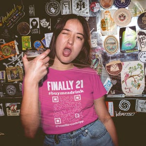Woman wearing a pink "Finally 21" t-shirt with a drink in hand, celebrating her 21st birthday with flair.