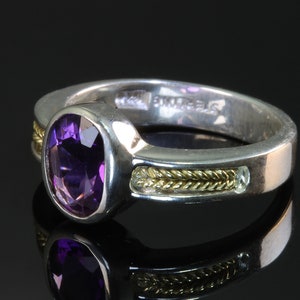 May include: A silver ring with a purple amethyst gemstone, a gold band, and the inscription "BVLGARI" on the inside.