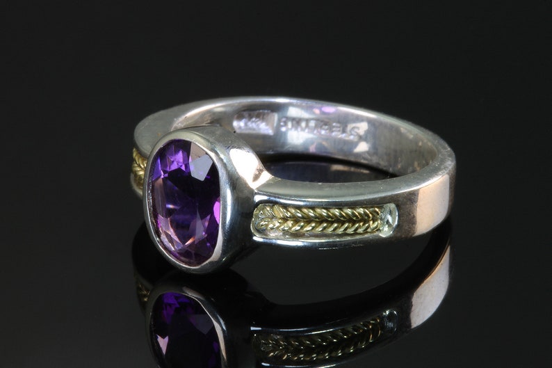 May include: A silver ring with a purple amethyst gemstone, a gold band, and the inscription "BVLGARI" on the inside.