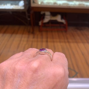 May include: A silver ring with a purple gemstone set in a bezel setting.