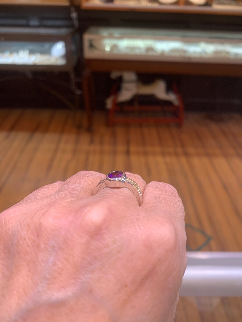 May include: A silver ring with a purple gemstone set in a bezel setting.