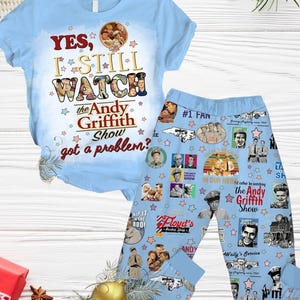 Könnte beinhalten: Ein blauer Schlafanzug mit einem kurzärmeligen T-Shirt und einer langen Hose. Das T-Shirt hat einen grafischen Aufdruck mit der Aufschrift "YES, I STILL WATCH the Andy Griffith Show got a problem?" Die Hose hat ein Muster aus Bildern der Andy Griffith Show, darunter Andy Taylor, Barney Fife und Opie Taylor. Die Hose hat auch ein Muster aus Sternen.