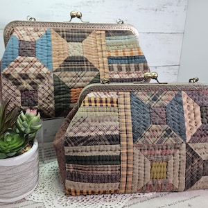 May include: Two quilted fabric purses with brass clasps. The larger purse is brown, beige, and blue with a plaid pattern. The smaller purse is brown, beige, and blue with a plaid pattern. Both purses have a quilted texture.