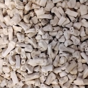 May include: A close-up image of a pile of small, white, bone-like pieces. The pieces are irregular in shape and have a rough texture.