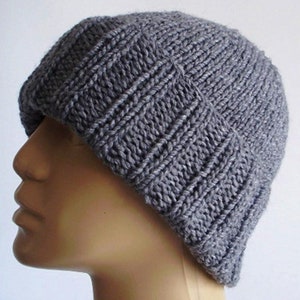 May include: A grey knitted beanie hat with a ribbed texture. The hat is made of a soft, warm material and is perfect for cold weather.