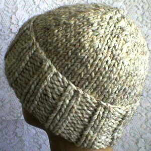 May include: A knitted hat in a light brown colour with a textured pattern. The hat is made of a soft, warm yarn and has a simple, classic design.