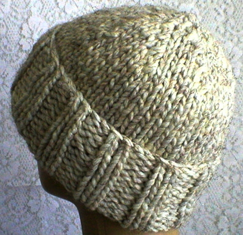 May include: A knitted hat in a light brown colour with a textured pattern. The hat is made of a soft, warm yarn and has a simple, classic design.
