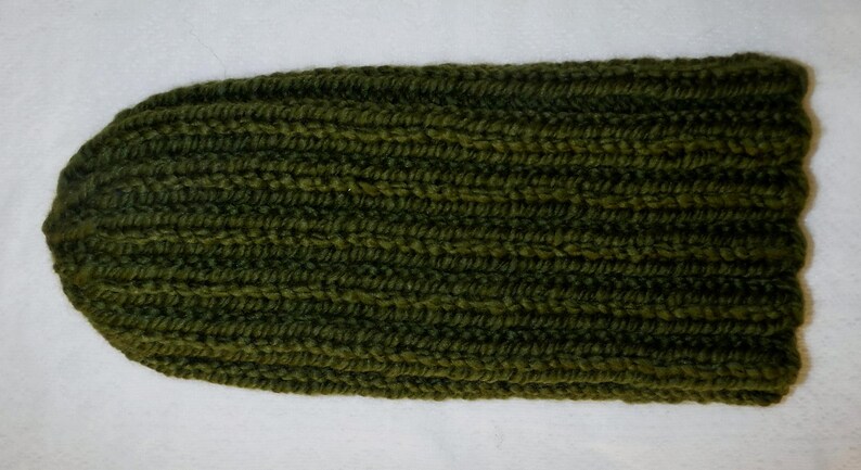 Op de afbeelding: Een olijfgroene gebreide beanie. De hoed is gemaakt van een dik, geribbeld gebreid materiaal. De hoed is effen van kleur en heeft een eenvoudig, klassiek ontwerp. Deze warme hoed is perfect voor koud weer.