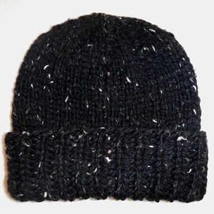 Puede incluir: Un gorro negro tejido con motas blancas. El gorro tiene un borde doblado y una textura acanalada. Este c&aacute;lido gorro de invierno es perfecto para el fr&iacute;o.