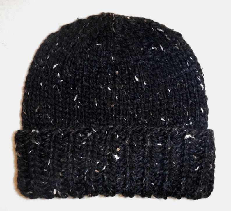 Puede incluir: Un gorro negro tejido con motas blancas. El gorro tiene un borde doblado y una textura acanalada. Este c&aacute;lido gorro de invierno es perfecto para el fr&iacute;o.