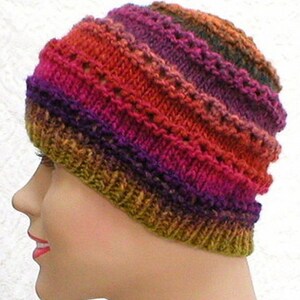 May include: A knitted hat with a multi-colored striped pattern in shades of orange, red, purple, and green.