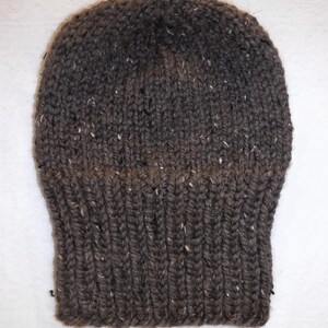 May include: A dark brown knitted beanie hat with a ribbed brim. The hat is made of a thick yarn with white flecks. The top of the hat has a tighter knit, creating a snug fit.