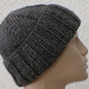 May include: A grey knitted beanie with a ribbed pattern. The beanie is folded down at the brim.